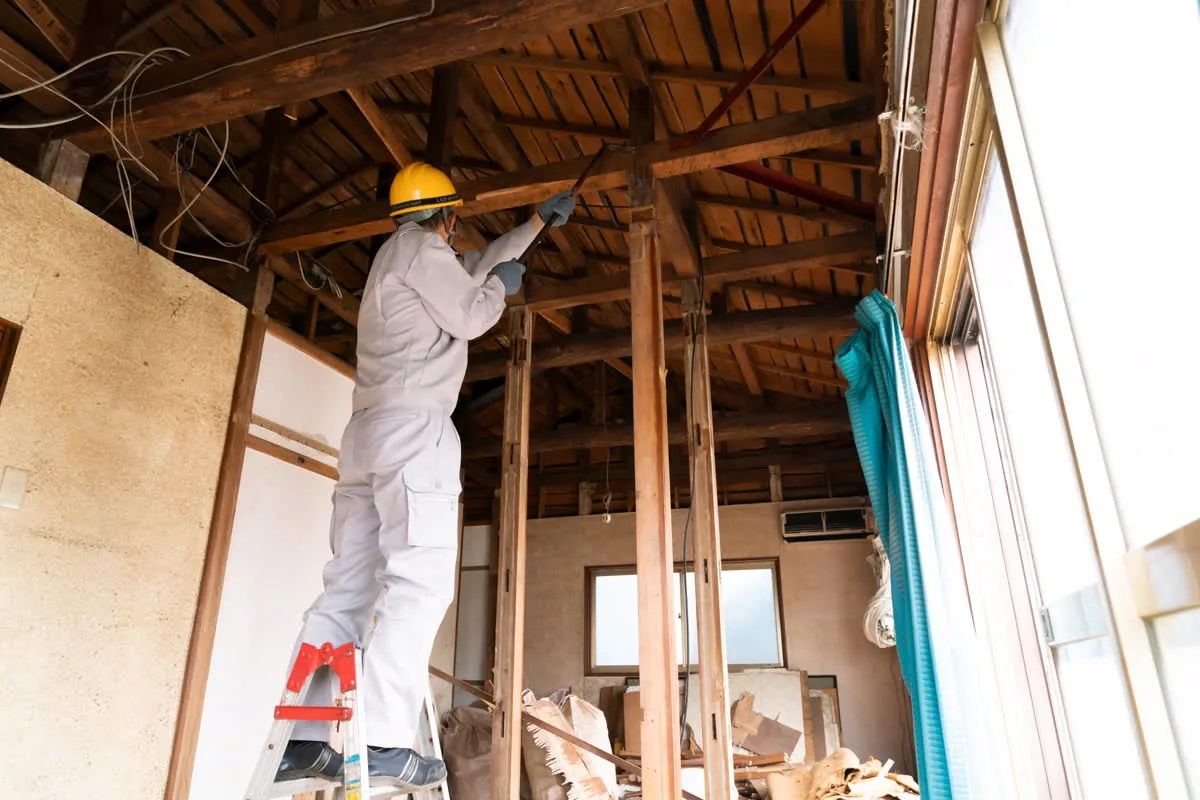防護服を着て木造住宅の内装を解体する作業員
