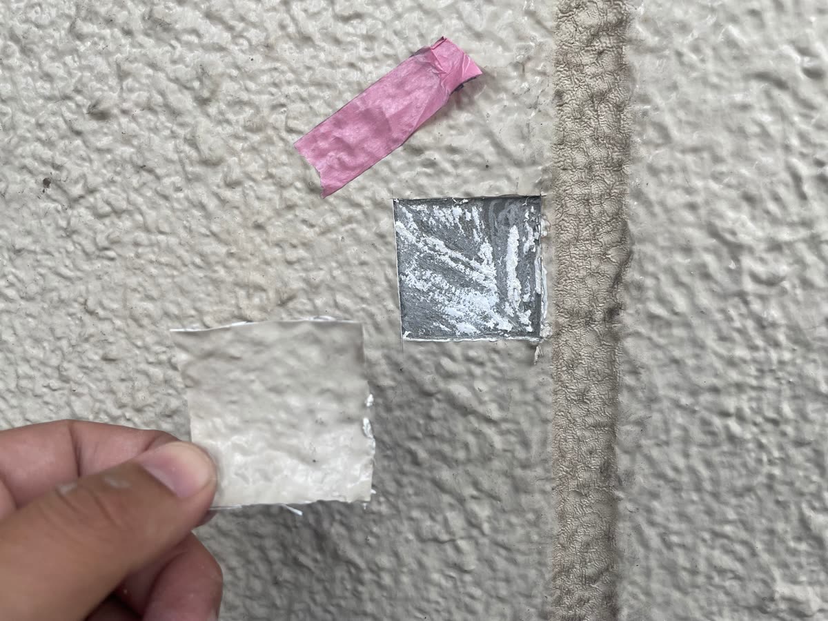 外壁から建材の一部を検体として切り取った跡と、目印のテープ