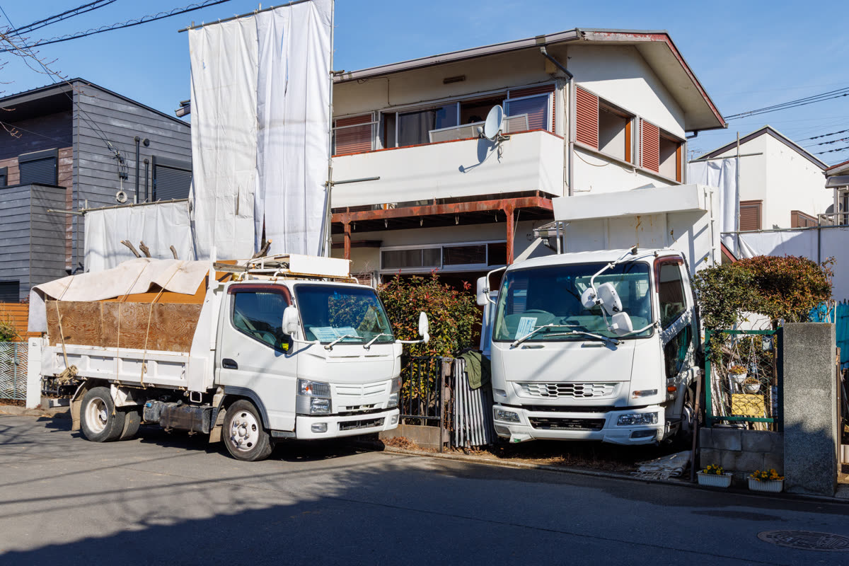 住宅街の解体現場と廃材を運ぶトラック